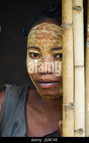 MADAGASCAR, Morondava - Agosto 8, 2011: Ritratto di giovane donna dal villaggio in una maschera di argilla su una faccia. Foto Stock