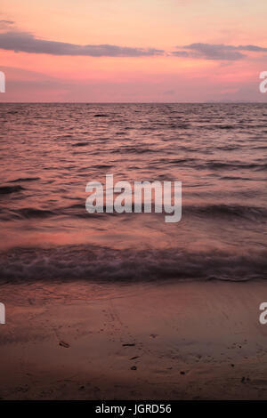 Rosa e viola del tramonto tropicale cielo sopra il mare ondeggiante, costa est della Thailandia Foto Stock