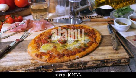 Versando l'olio d'oliva sopra una pizza italiana margherita Foto Stock