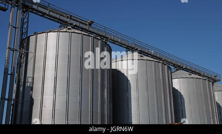 Acciaio silos per il grano utilizzato per immagazzinare grano. Grano deposito bidoni contro il cielo blu. Foto Stock