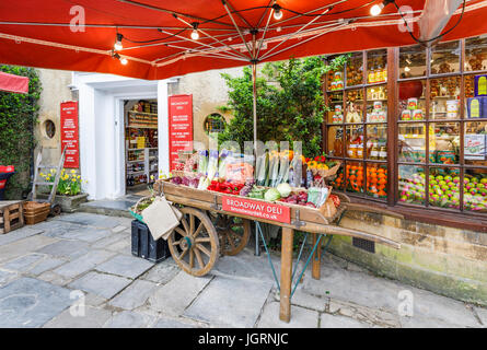 Frutta colorata barrow visualizzatore esterno fruttivendolo shop, Broadway, Worcestershire, un bellissimo villaggio in Cotswolds, sud-ovest Inghilterra Foto Stock