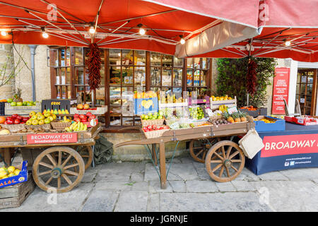 Frutta colorata barrow visualizzatore esterno fruttivendolo shop, Broadway, Worcestershire, un bellissimo villaggio in Cotswolds, sud-ovest Inghilterra Foto Stock