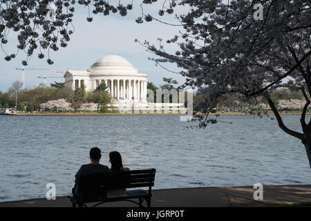 Silhouette di un giovane su un banco vicino al Jefferson Memorial durante il Washington DC Cherry Blossom Festival Foto Stock