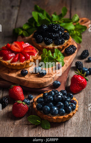 Freschi Fatti in casa crostate berrie con mirtilli, blackberry e fragole su sfondo di legno Foto Stock