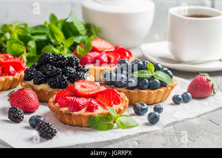 Freschi Fatti in casa crostate berrie con mirtilli, blackberry e fragole su sfondo grigio Foto Stock