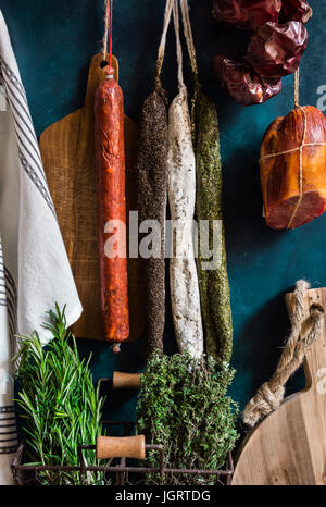 Assortimento di spagnolo cured varietà di carne, salsicce, chorizo, longaniza, lomo, salumi su sfondo scuro, legno tagliere, erbe aromatiche fresche, rusti Foto Stock