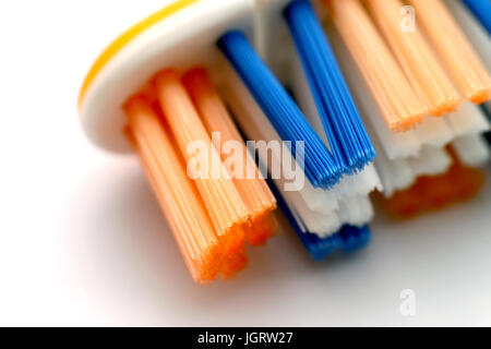 Nuovo spazzolino da denti con giallo, blu e bianco setole su base in plastica isolato su uno sfondo bianco. Girato in macro. Foto Stock