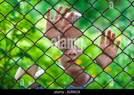 Immagine astratta di un ragazzino che dietro la catena collegamento recinto. Foto il concetto di combinazione Foto Stock