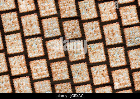Sullo sfondo di piazza rettangolare di biscotti dolci closeup su uno sfondo nero. Un sacco di fritto croccante di biscotti disposti in uno schema a scacchiera Foto Stock