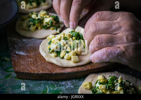 Nonna cuochi torte. Home il cibo cotto. omemade dolci di pasta in le mani delle donne. Il processo per la fabbricazione di pasta di torta a mano Foto Stock