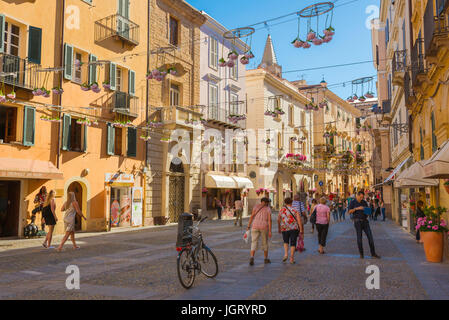 Alghero Piazza Civica, persone passeggiata attraverso la Piazza Civica nello storico quartiere della città vecchia di Alghero, in Sardegna. Foto Stock
