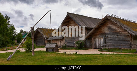 Paesaggio rurale. Un legno casa rurale con un tetto coperto di muschio. In primo piano vi è una recinzione di legno fatta di poli.La Russia, Pskov Regione Foto Stock