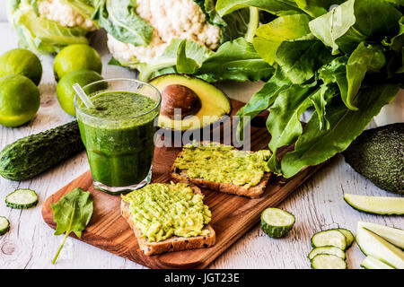 Frullato di verde e due panini con avocado. sano cibo vegan Foto Stock