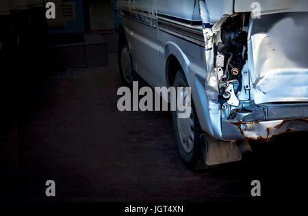 Una macchina con un faro rotto e la ruggine in garage su uno sfondo nero con posto per il testo Foto Stock