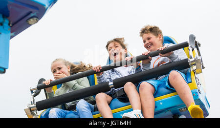 Giovani amici a cavallo sul Galaxia giro sul molo di Brighton in estate. Foto Stock