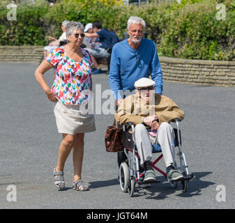 Anziani disabili uomo essendo spinto in una sedia a rotelle. Foto Stock