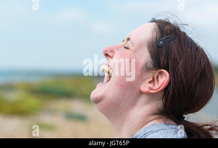 Felice giovane donna con la bocca aperta ridendo hysterically fino a quando non si fa male. Foto Stock