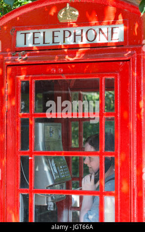 K6 nella casella Telefono. Donna che utilizza il telefono in un vecchio BT K6 nella casella Telefono che recentemente è stata dipinta nel Regno Unito. Foto Stock