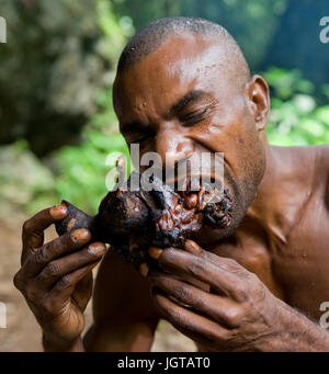 Nuova Guinea, Indonesia - 13 gennaio: Uomo tribù Yaffi mangiare un pezzo di carne. Foto Stock