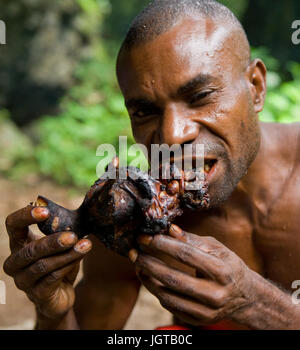 Nuova Guinea, Indonesia - 13 gennaio: Uomo tribù Yaffi mangiare un pezzo di carne. Foto Stock