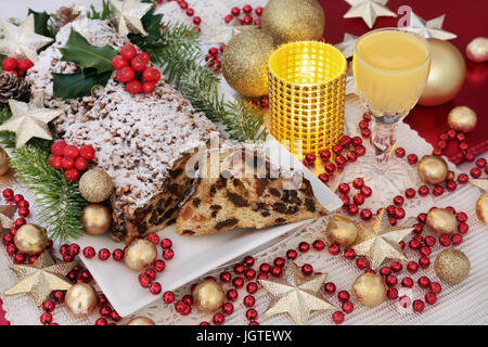 Cioccolatino natalizio stollen la torta su un piatto con uovo nog, agrifoglio, fir ed edera e oro ninnolo e cordone rosso decorazioni. Foto Stock