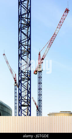 Quattro gru a torre in un cantiere nel centro di un quartiere degli affari in pieno sviluppo. Foto Stock