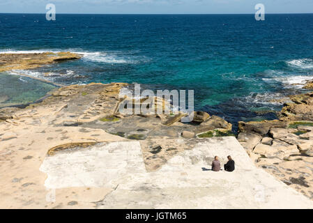 Le rocce calcaree shore sulla costa a St Julians Bay Malta su una soleggiata giornata estiva Foto Stock