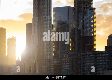 La luce del tramonto risplende attraverso la città di New York skyline di moderni edifici di stile nel centro di Manhattan NYC Foto Stock