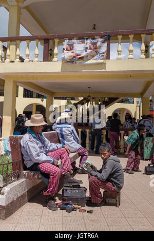 La vita di strada in Todos Santos Cuchumatán, indigeni del Guatemala nel loro abbigliamento tradizionale, lucidascarpe, boy pulisce le scarpe. Foto Stock