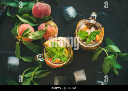 Estate rinfrescante freddo pesca ice tea con menta fresca in vasetti di vetro sul vassoio di metallo sfondo, vista dall'alto Foto Stock