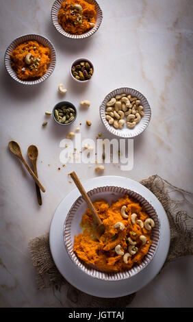 Halwa carota / Budino di carote con i dadi in una ciotola in ceramica sulla parte superiore vista su di una tavola di marmo Foto Stock