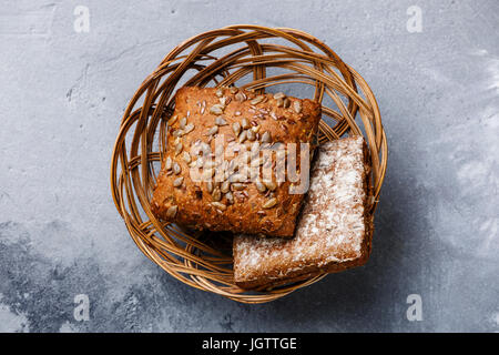 I cereali freschi la pagnotta di pane con semi di girasole nel cesto di vimini sul cemento grigio sfondo Foto Stock