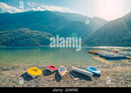 Cross-immagine elaborata del bellissimo lago Kournaskayak circondato da montagne e pagaia noleggio della barca al tramonto, Creta, Grecia Foto Stock