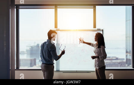 Imprenditrice fare una presentazione di idee sulla lavagna nella sala riunioni. Due colleghi per discutere idee di business in ufficio. Foto Stock