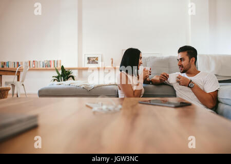 Coppia giovane rilassante dal lettino con tazza di caffè nella stanza vivente. L uomo e la donna seduta insieme a casa un caffè e parlare. Foto Stock