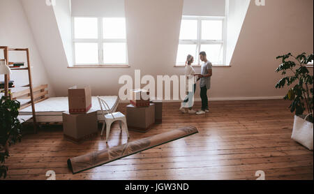 Coppia giovane in amore muovendo in un nuovo appartamento. L uomo e la donna in piedi insieme con caselle e tappeto sul pavimento. Foto Stock