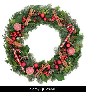 Decorativa ghirlanda di Natale con decorazioni ninnolo, candy canes, bastoncini di cannella, mele smerigliato, agrifoglio, vischio, ivy e coperta di neve verde. Foto Stock