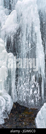 Anno intorno a molla dei flussi di acqua in drappi di ghiaccio a temperature sotto lo zero. Foto Stock