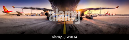 Hainan Airlines Airbus A330 visto da sotto la fusoliera viene rifornito su asfalto in aeroporto di Pechino PEK durante il sunrise Foto Stock