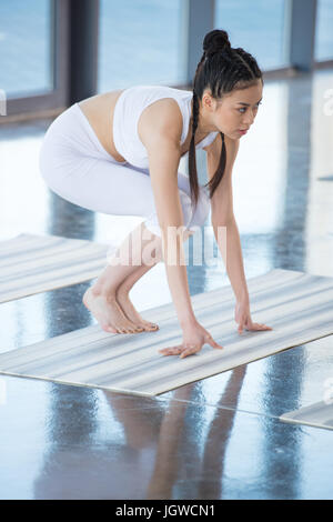 Vista laterale della donna asiatica Gru praticanti pongono sulla posa di yoga Foto Stock