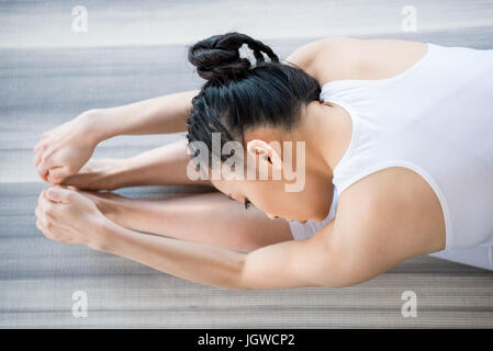 Giovane donna a praticare Yoga in flessione in avanti pone Foto Stock