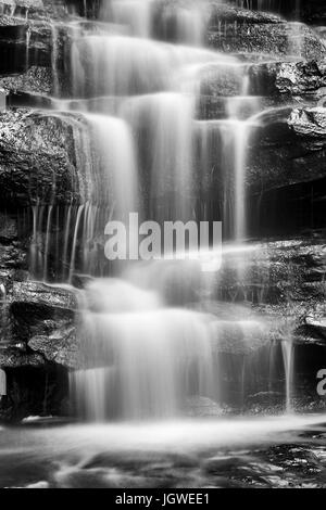 Bianco nero sfocato flusso di acqua che scorre verso il basso le rocce di arenaria in Australia centrale nella foresta pluviale della costa vicino a Gosford - Somersby cade. Foto Stock