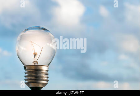 Accesa lampadina luce con il blu del cielo al di fuori e le nuvole in background Foto Stock