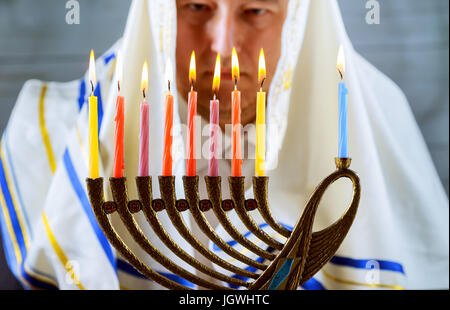 Hanukkah, una celebrazione Ebraica. Candele accese in la menorah, l'uomo in background. Foto Stock