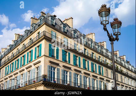 Un tipico edificio in stile haussmanniano, a Parigi con balconi e persiane e una strada luce in primo piano sotto una luce calda del tardo pomeriggio. Foto Stock