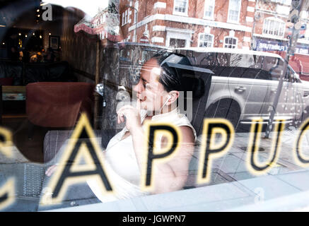 Vista attraverso la finestra di lavoro imprenditrice nel caffè bar Foto Stock