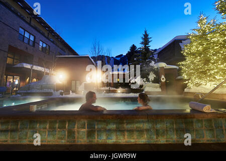 Coppia matura il relax in hotel outdoor vasca calda al tramonto, Aspen, Colorado, STATI UNITI D'AMERICA Foto Stock