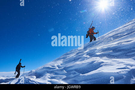 Due sciatori maschio trascinarsi faticosamente fino coperta di neve montagna, Aspen, Colorado, STATI UNITI D'AMERICA Foto Stock