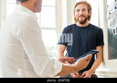 I progettisti di sesso maschile con tavoletta digitale presso il creative studio meeting Foto Stock