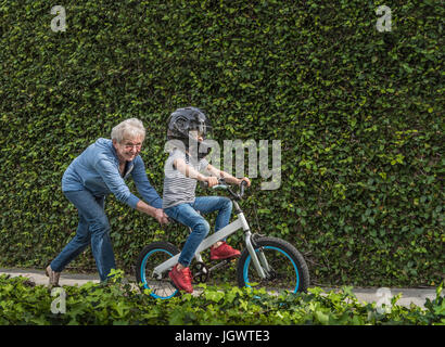 Nonna nipote di spinta sulla sua bicicletta Foto Stock